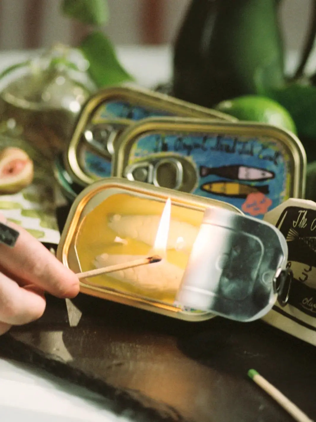 Tinned Fish Candle in Olive Oil Sea Salt being lit with a match on a table | Twentyseven Toronto