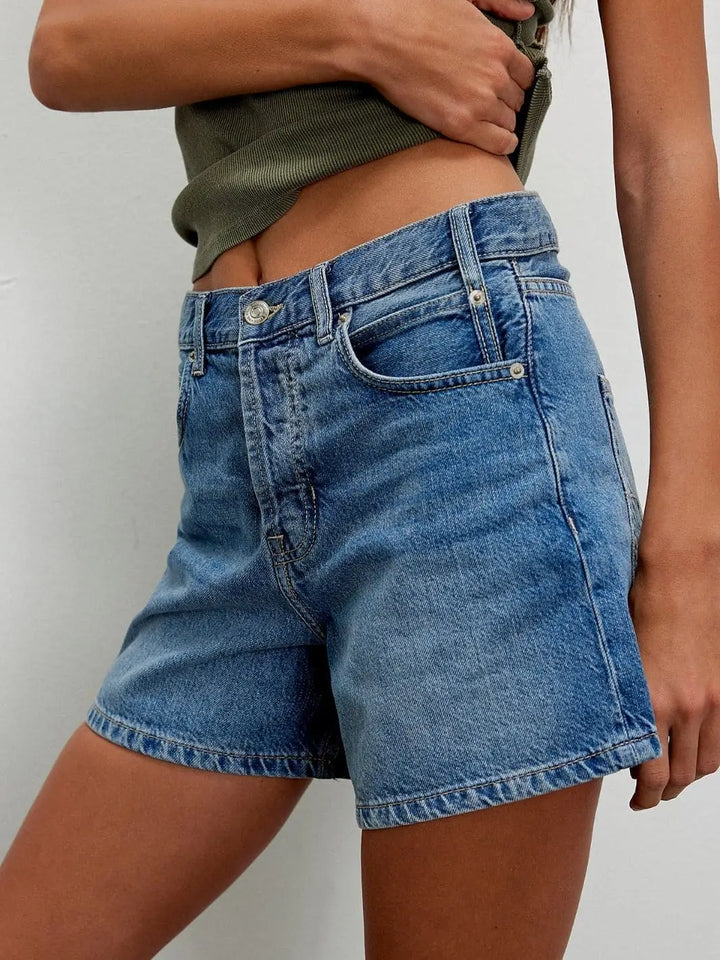 A side-angle view captures the high-rise waistband, classic five-pocket design, and relaxed leg openings of the medium-wash denim shorts | Twentyseven Toronto
