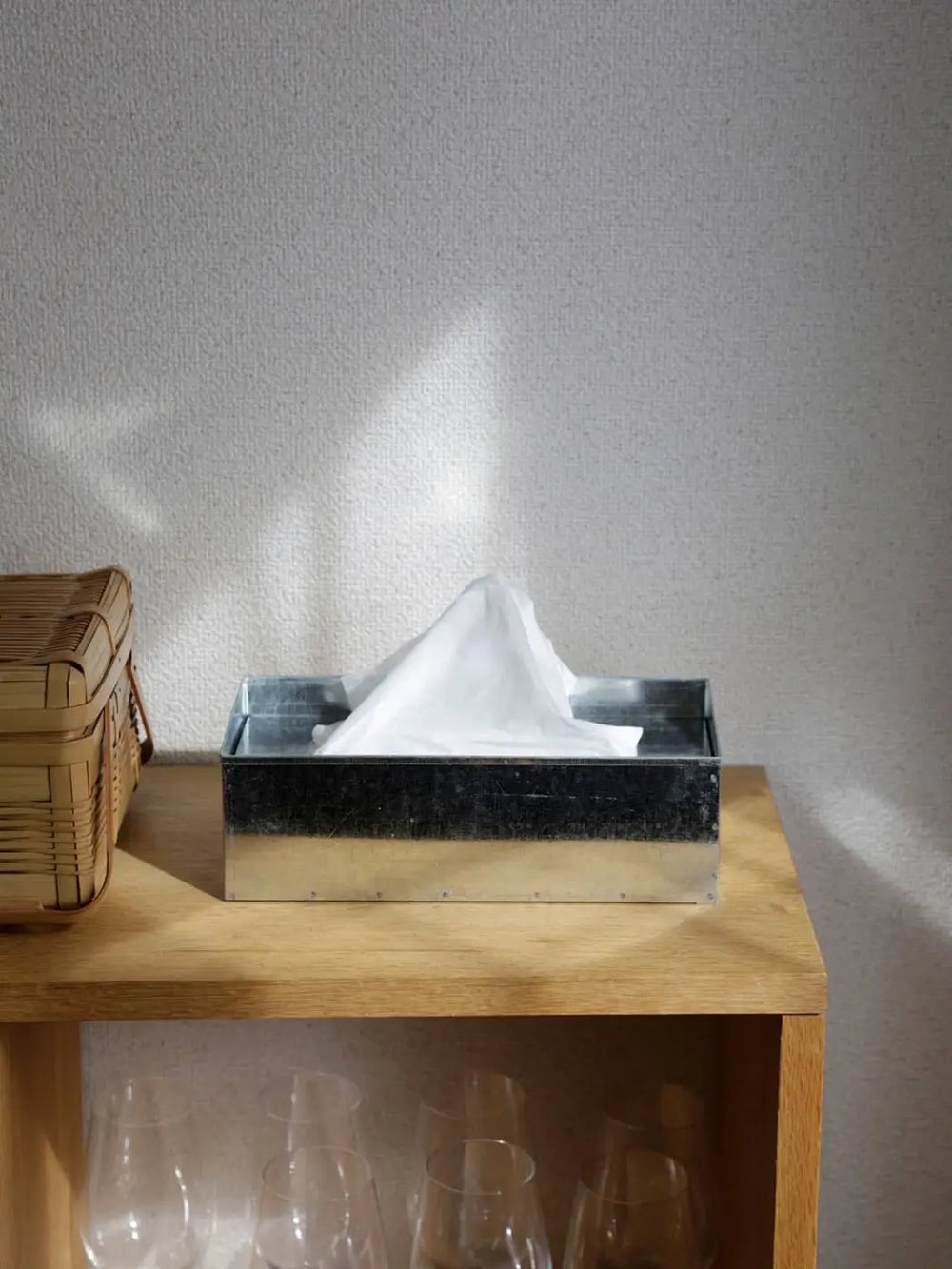 A Fog Linen Work Tissue Box made of industrial galvanized steel sits on a light wooden shelf in a sunlit room | Twentyseven Toronto