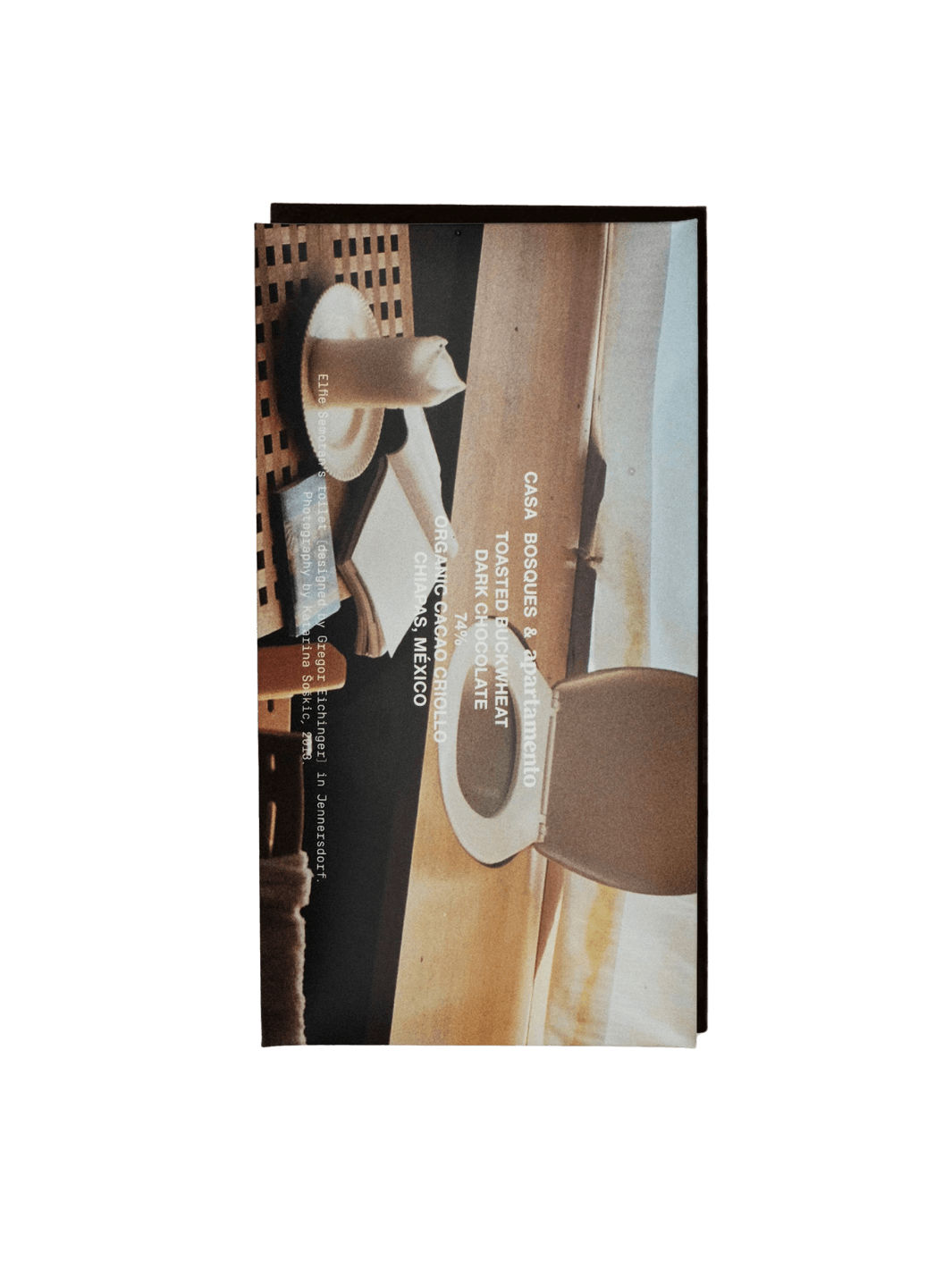 Packaging for the Toasted Buckwheat X Apartmento Chocolate Bar from Casa Bosques features an artistic photograph of a minimalist interior with a lit candle and a wooden chair | Twentyseven Toronto