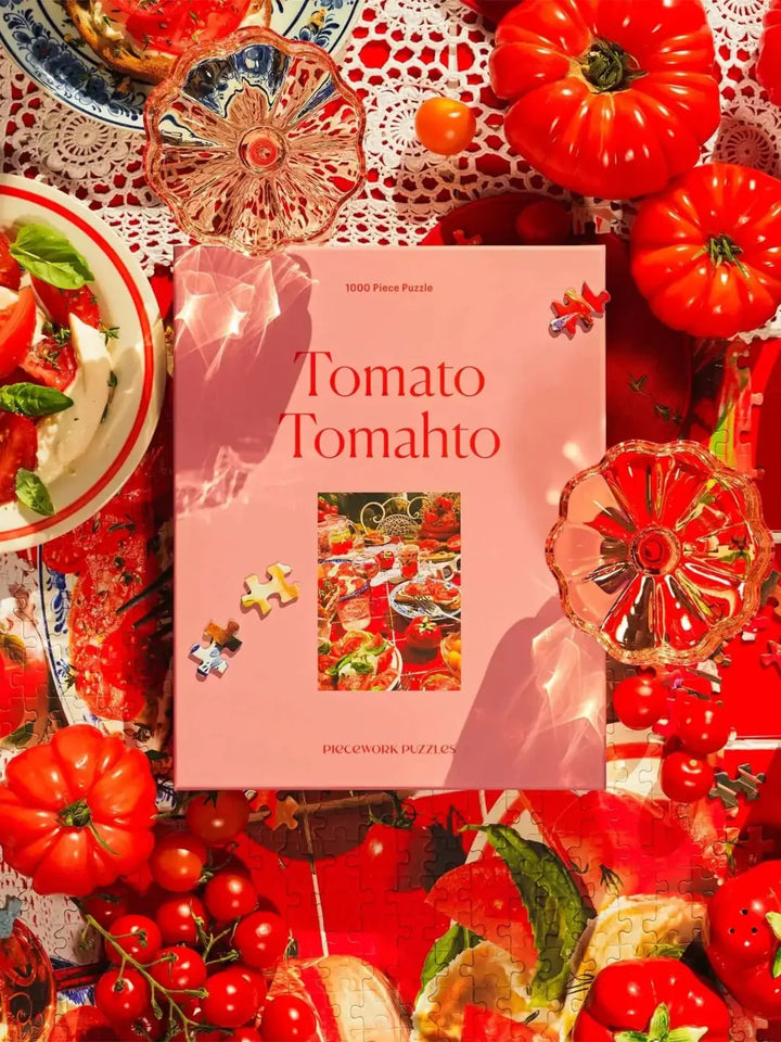 Puzzle box titled 'Tomato Tomahto' from Piecework Puzzles surrounded by tomatoes and kitchen items on a red and white tablecloth | Twentyseven Toronto