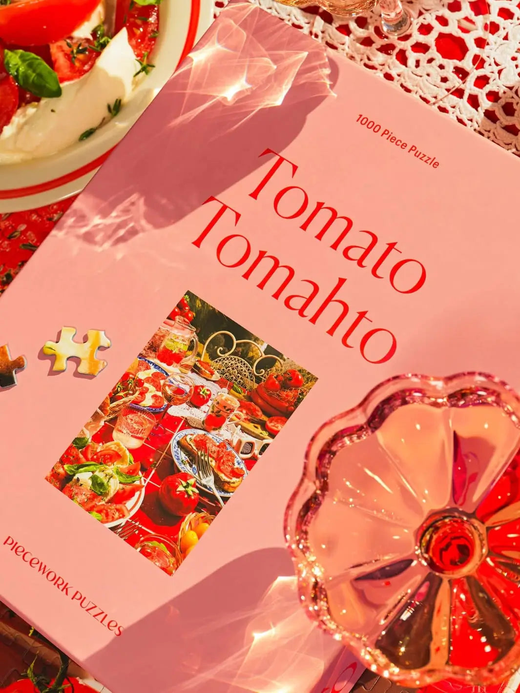 Puzzle box titled 'Tomato Tomahto' 1000 piece puzzle from Piecework Puzzles with a decorative glass item on a table | Twentyseven Toronto