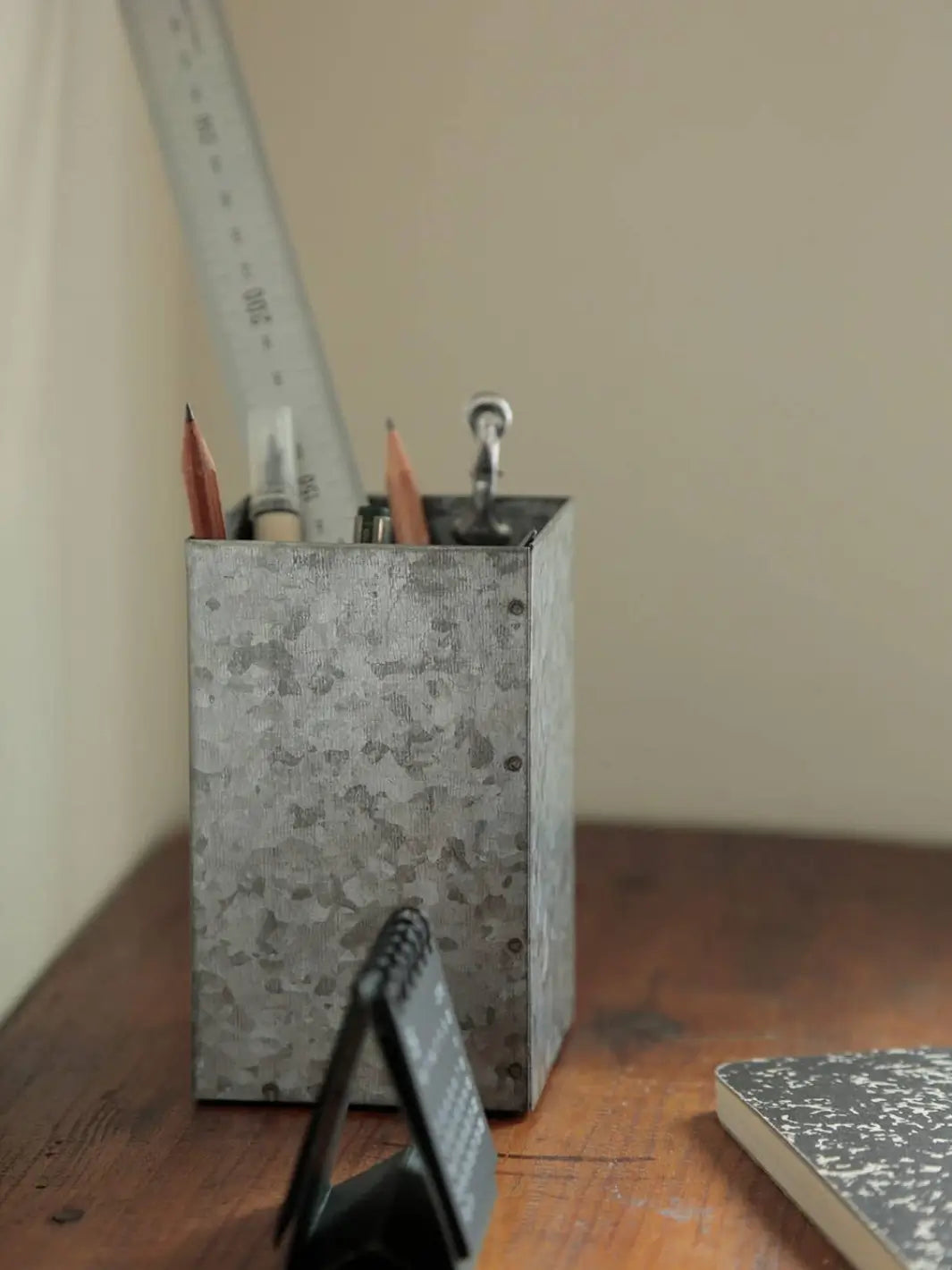 A Fog Linen Work Tool Stand sits on a wooden desk, functioning as a rustic stationery holder for pencils, pens, and a metal ruler | Twentyseven Toronto