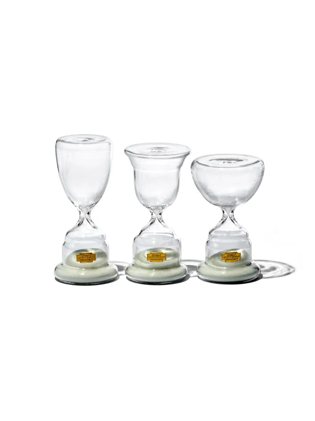Group display of three unique glass hourglass designs, with the wide-bowled Trophy Shaped Sandglass White No.3 from Puebco standing on the far right | Twentyseven Toronto
