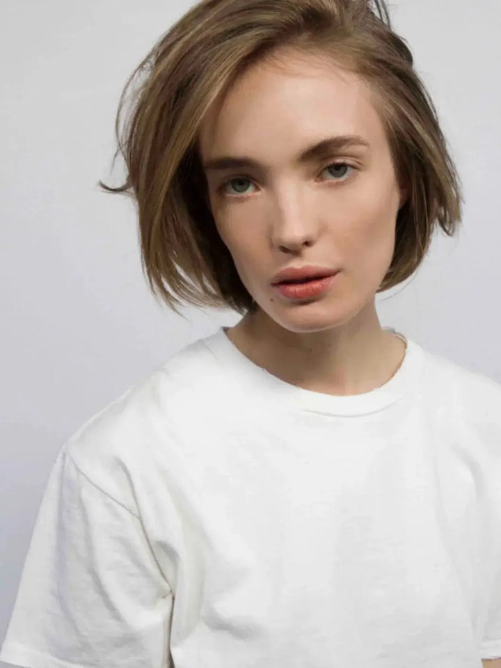 A model with a short, light brown bob showcases natural volume and separation achieved with R+Co TROPHY Shine + Texture Spray | Twentyseven Toronto