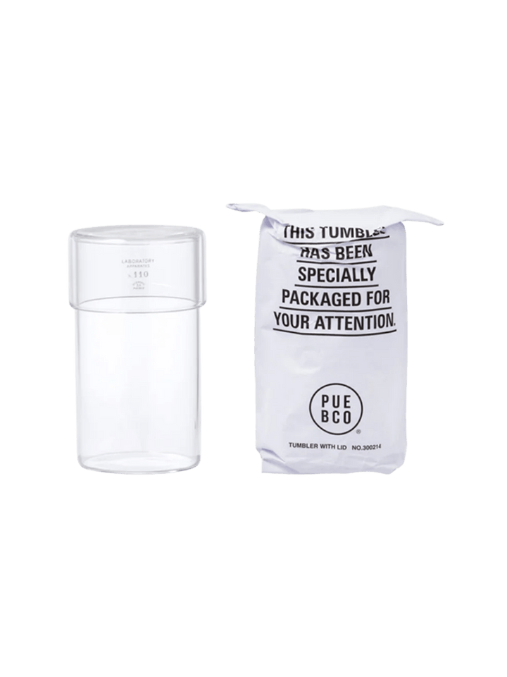 Clear glass Tumbler With Lid from Puebco standing beside its signature stamped paper packaging | Twentyseven Toronto