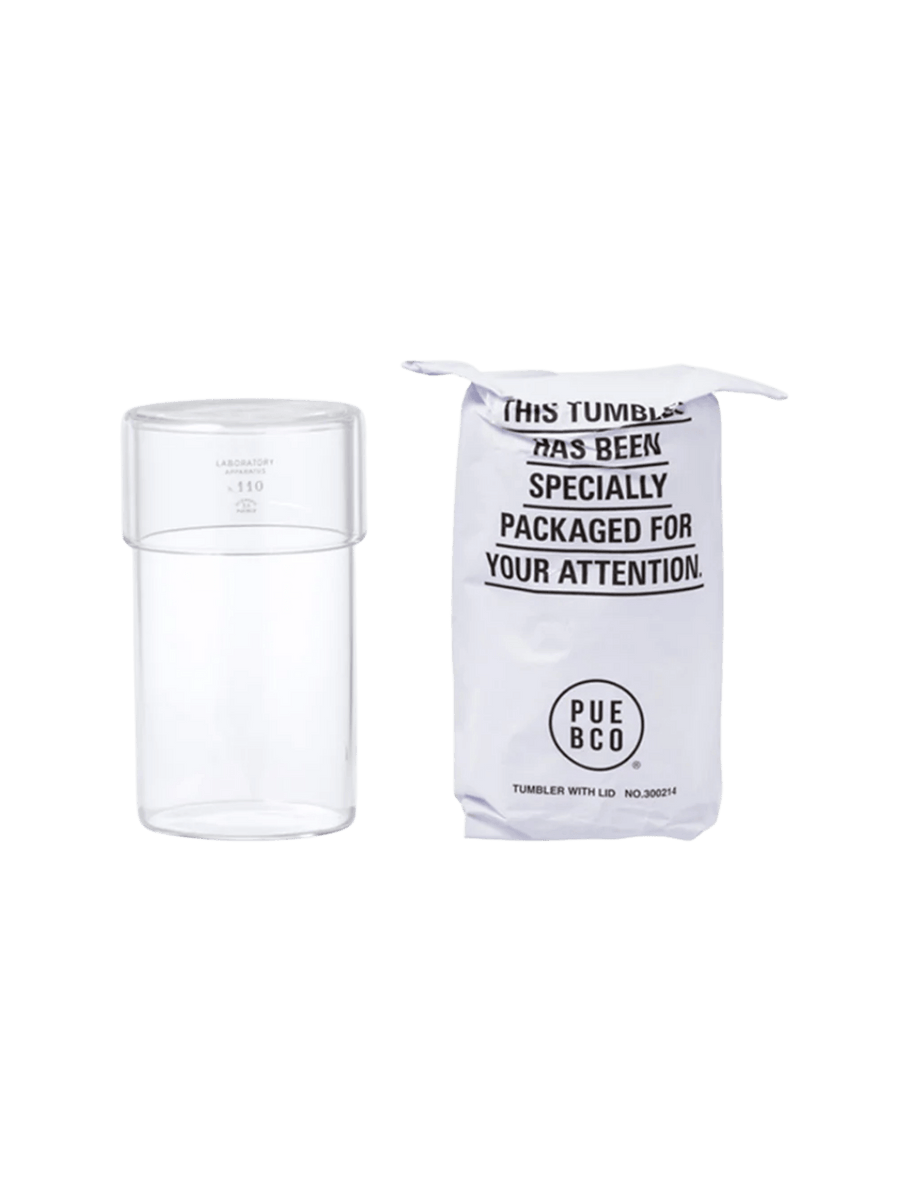 Clear glass Tumbler With Lid from Puebco standing beside its signature stamped paper packaging | Twentyseven Toronto