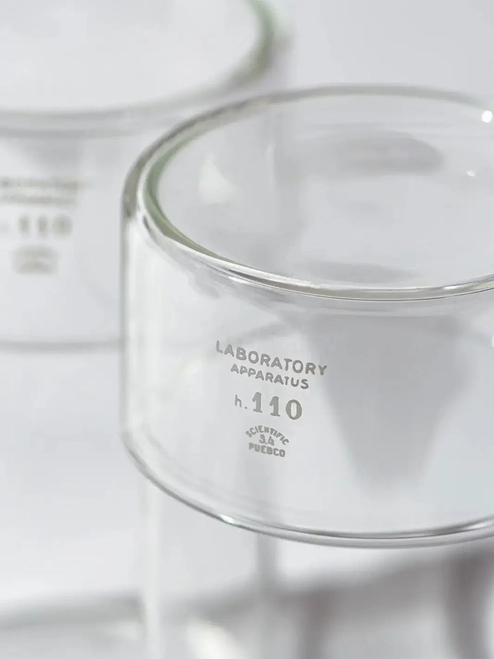 Close-up detail shot focusing on the white printed text on the glass surface of the Tumbler With Lid from Puebco, reading "LABORATORY APPARATUS h. 110 SCIENTIFIC PUEBCO" | Twentyseven Toronto