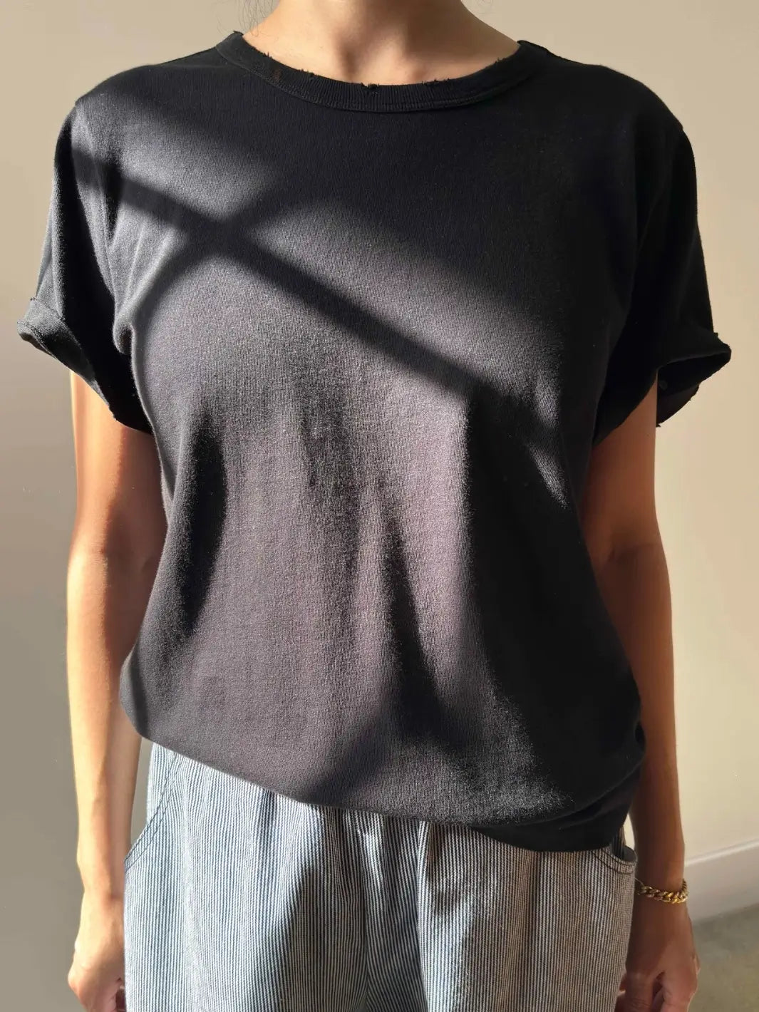 A front-facing view of a person modeling the Le Bon Shoppe Vintage Boy Tee - True Black paired with striped trousers | Twentyseven Toronto