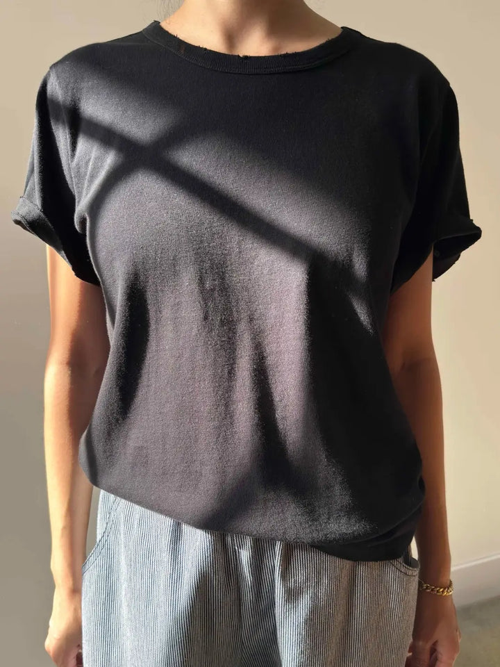 A front-facing view of a person modeling the Le Bon Shoppe Vintage Boy Tee - True Black paired with striped trousers | Twentyseven Toronto