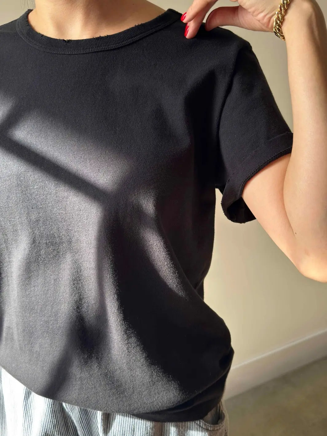 A close-up shot focuses on the texture, cuffed sleeve, and raw-edge neckline details of the Le Bon Shoppe Vintage Boy Tee - True Black as worn by a model | Twentyseven Toronto