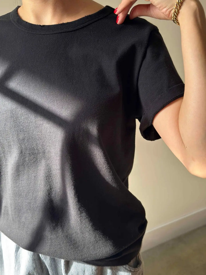 A close-up shot focuses on the texture, cuffed sleeve, and raw-edge neckline details of the Le Bon Shoppe Vintage Boy Tee - True Black as worn by a model | Twentyseven Toronto
