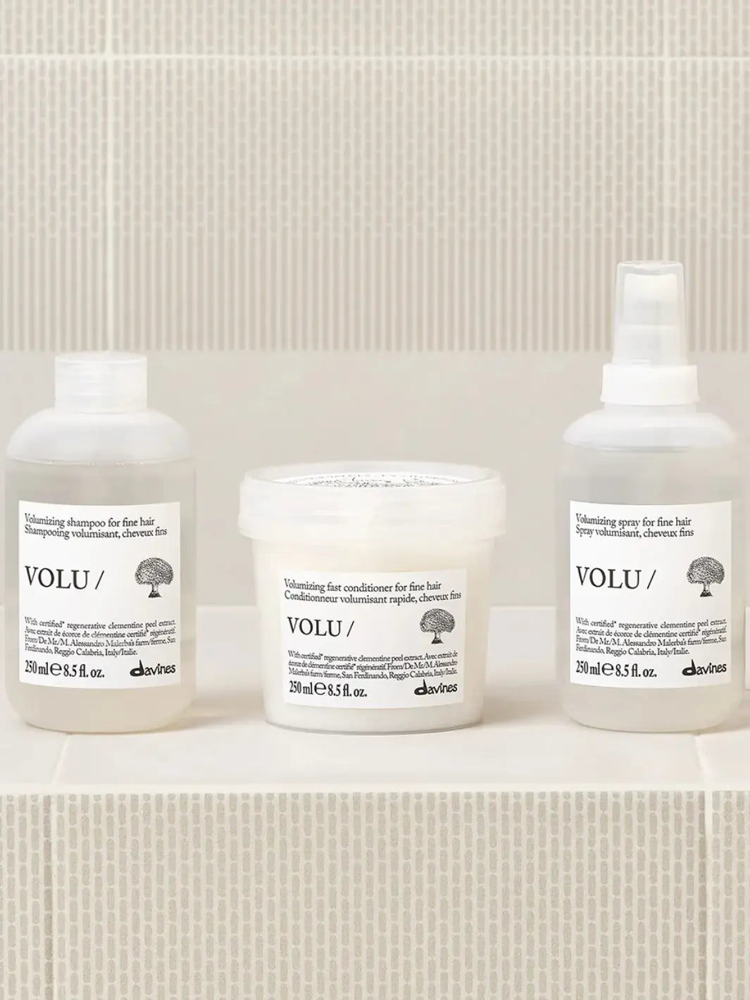 The Davines VOLU Set for fine hair, featuring the volumizing shampoo, fast conditioner, and volumizing spray lined up on a tiled surface | Twentyseven Toronto