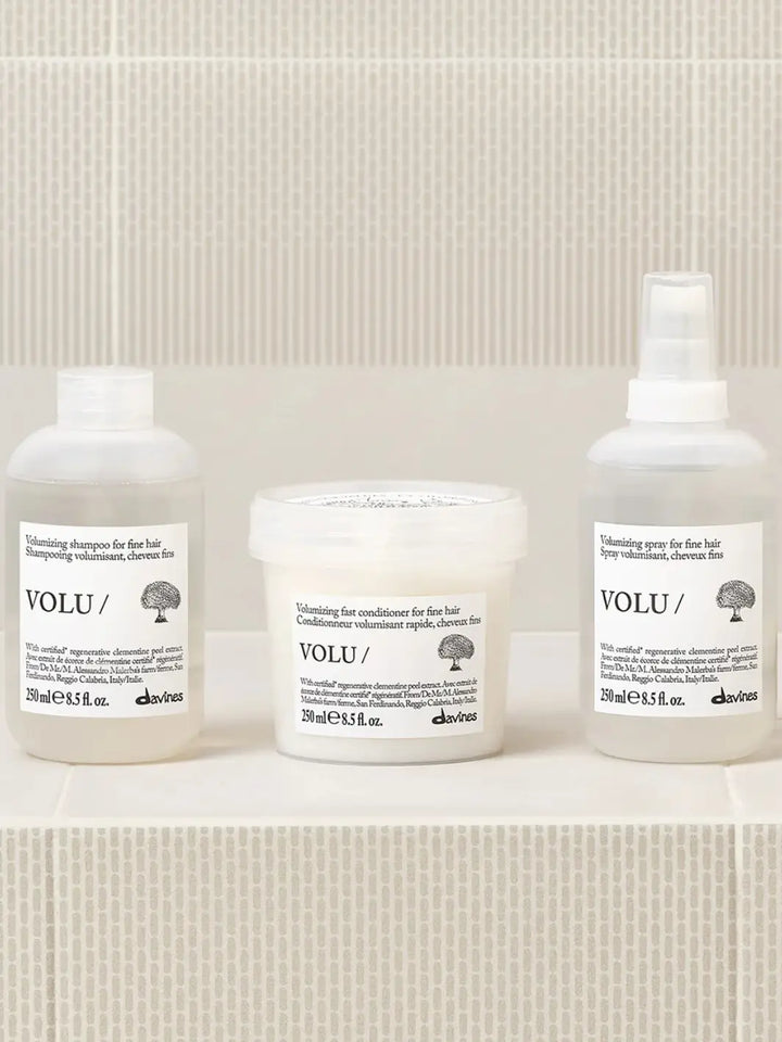 The Davines VOLU Set for fine hair, featuring the volumizing shampoo, fast conditioner, and volumizing spray lined up on a tiled surface | Twentyseven Toronto