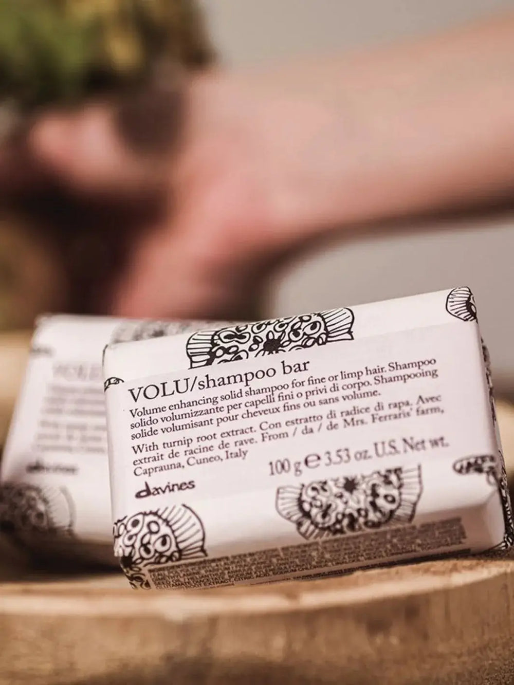 A close-up shot shows a wrapped Davines VOLU Shampoo Bar sitting in a wooden dish near other bars | Twentyseven Toronto
