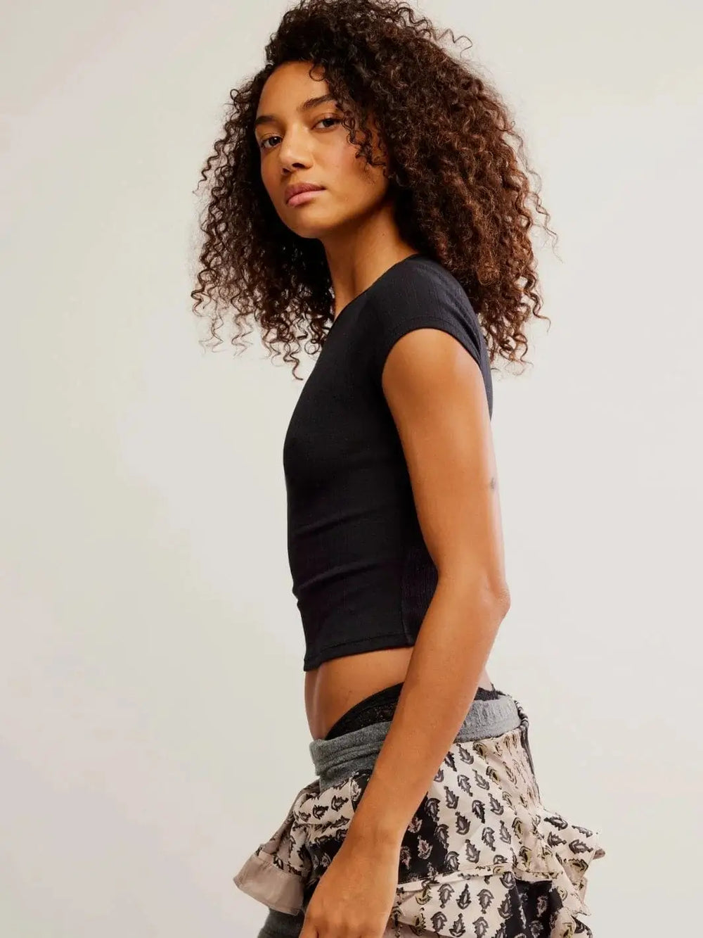 A side profile view highlights the cropped length, fitted silhouette, and cap sleeves of the Free People Wait A Minute Baby Tee in Anthracite | Twentyseven Toronto