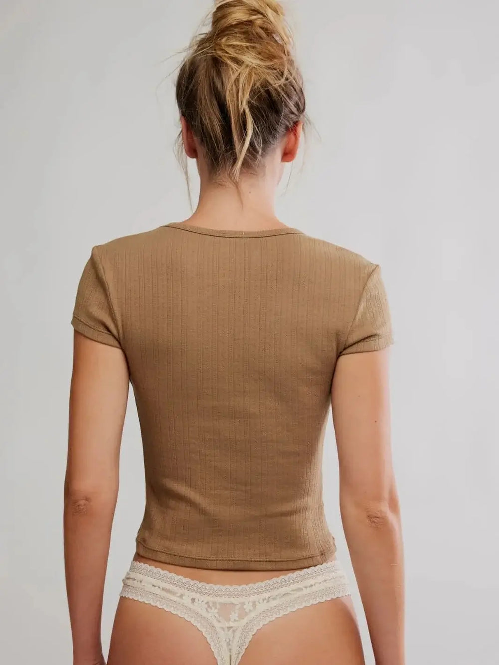 A direct rear view showcases the form-fitting construction and clean stitching details along the hem and sleeves of the Free People Wait A Minute Baby Tee in Antique Bronze | Twentyseven Toronto