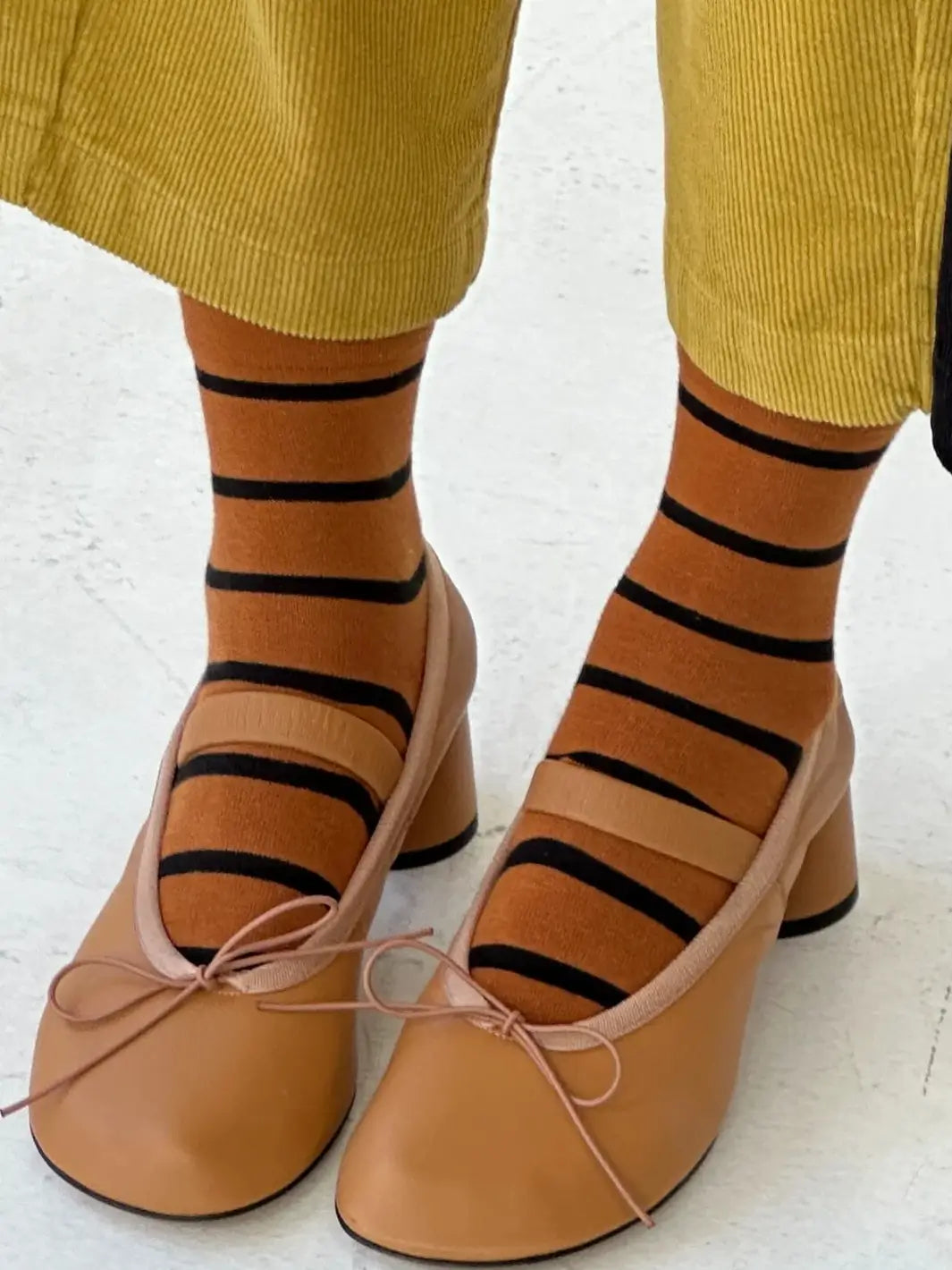 A person styles the striped Wally Socks in Camel from Le Bon Shoppe with tan leather low-heeled Mary Janes and yellow corduroy trousers | Twentyseven Toronto