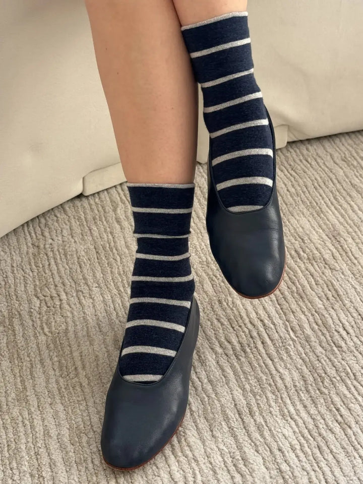 A close-up view shows a person styling the striped Wally Socks in Marine from Le Bon Shoppe with classic navy blue leather ballet flats | Twentyseven Toronto
