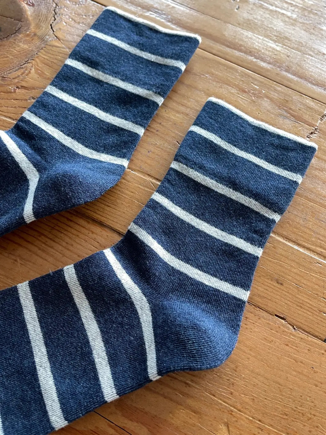 A close-up shot captures the cozy texture of the striped Wally Socks in Marine from Le Bon Shoppe resting on a rustic wooden table | Twentyseven Toronto