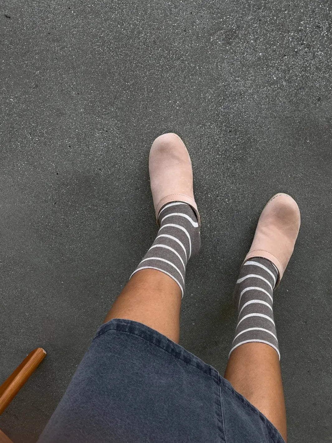 A top-down view shows a person wearing the striped Wally Socks in Mocha from Le Bon Shoppe styled with pale pink slip-on clogs and a denim skirt | Twentyseven Toronto