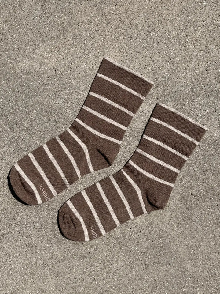 A pair of brown and cream striped Wally Socks in Mocha from Le Bon Shoppe is displayed flat on a textured concrete surface | Twentyseven Toronto