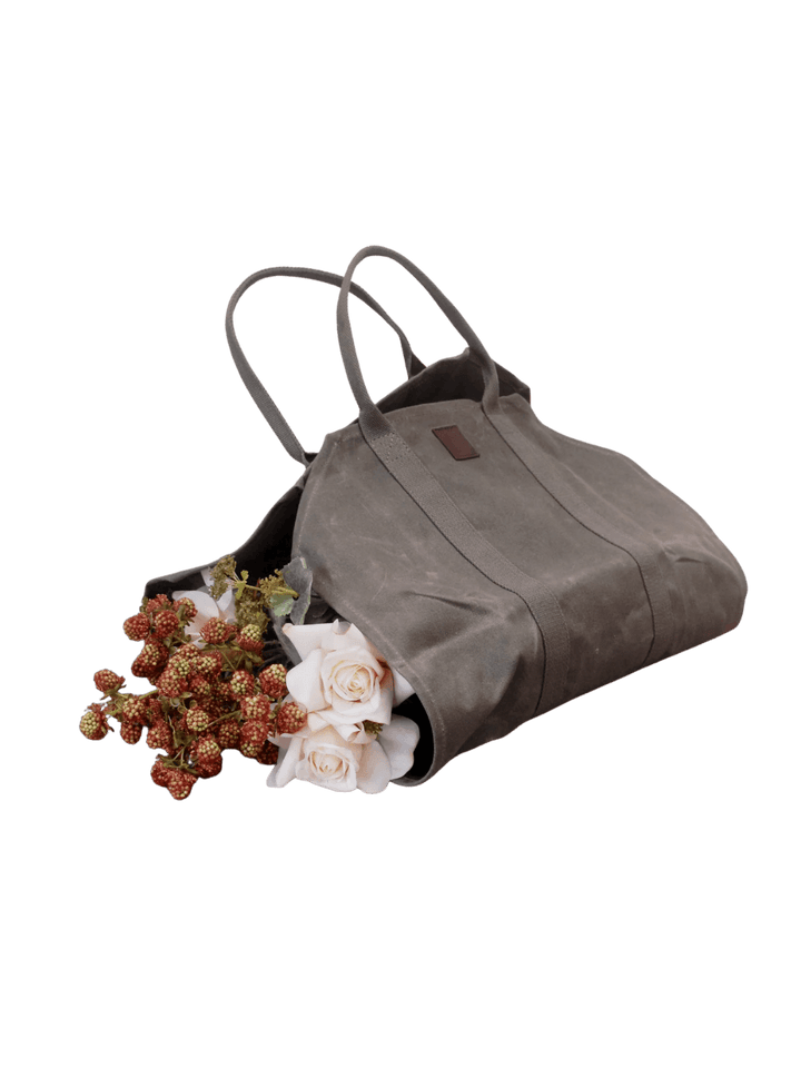 An olive green Waxed Canvas Log Flower Holder from Earth and Nest filled with fresh white roses and flowers on a transparent background | Twentyseven Toronto