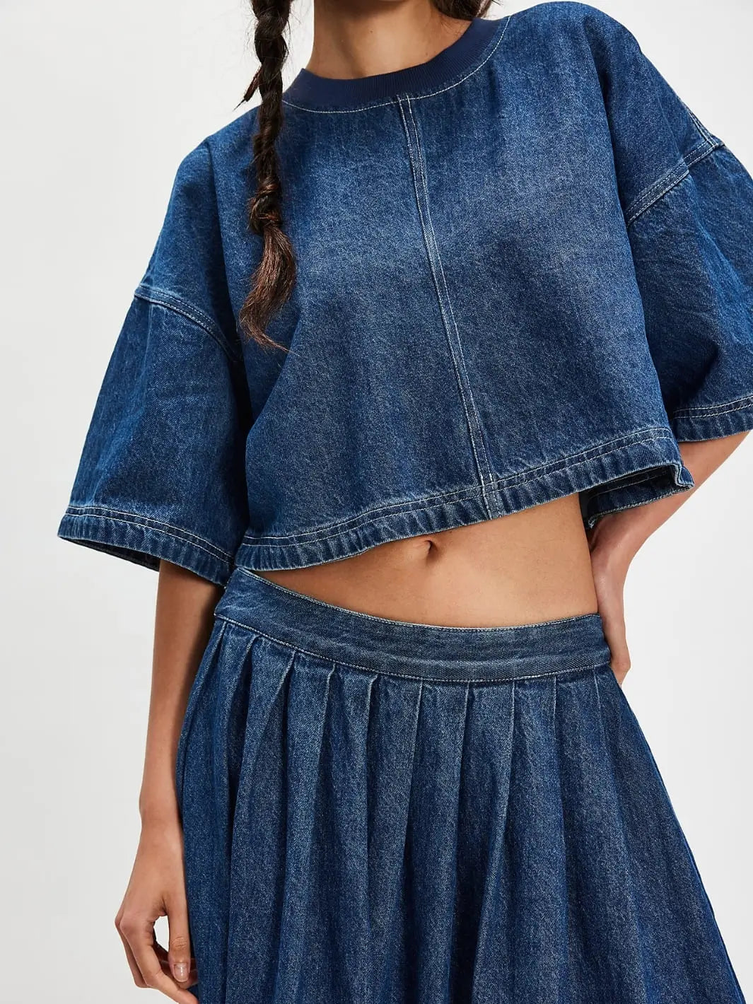A close-up front view highlights the cropped hem, central seam detailing, and matching pleated skirt of the two-piece Free People Westley Denim Skirt Set in Deep Sea Wash | Twentyseven Toronto