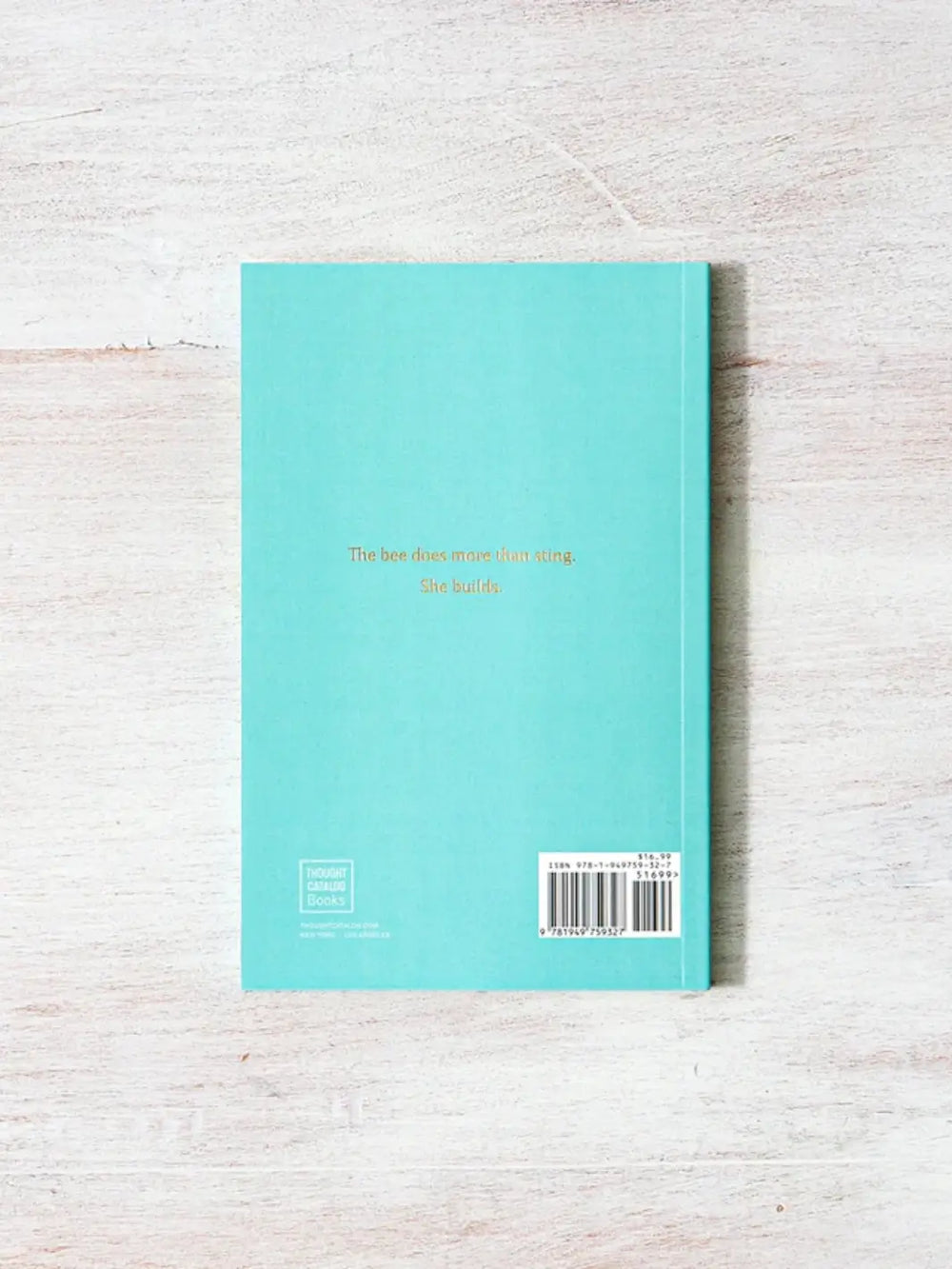 Turquoise back cover of When The Bee Stings by Raquel Franco features the gold foil quote, "The bee does more than sting. She builds," above the publisher's barcode and logo | Twentyseven Toronto