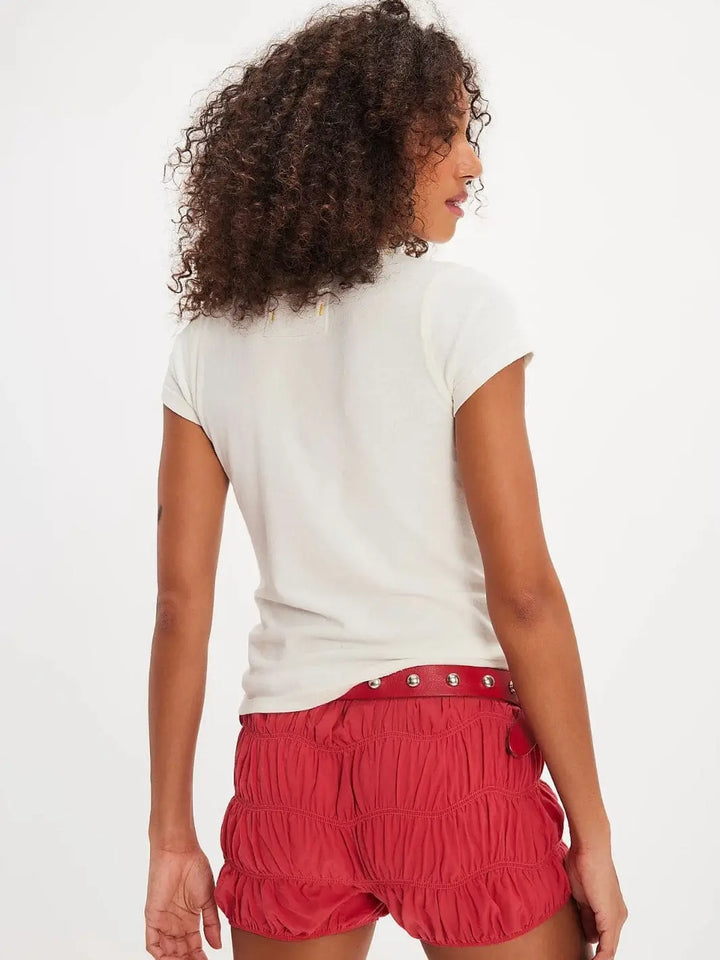 A rear view captures the clean back panel, capped sleeves, and fitted silhouette of the Free People Wild Country Tee - Colorado Combo styled with textured red shorts | Twentyseven Toronto