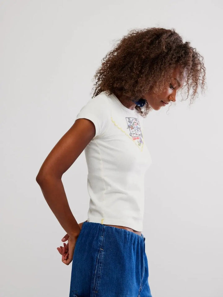 A side profile view highlights the short capped sleeves and contouring fit of the white Free People Wild Country Tee - Colorado Combo paired with blue denim | Twentyseven Toronto