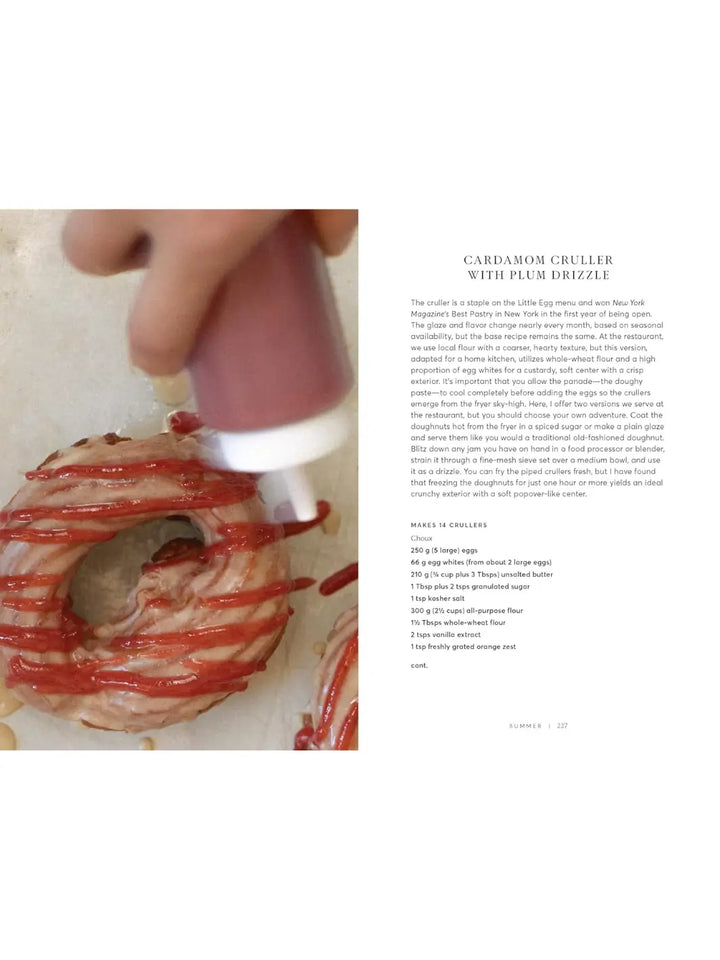 Recipe for a Cardamom Cruller with Plum Drizzle from Will This Make You Happy: Stories & Recipes from a Year of Baking by Tanya Bush, accompanied by an action shot of a vibrant red plum sauce being squeezed over a golden, ring-shaped pastry | Twentyseven Toronto