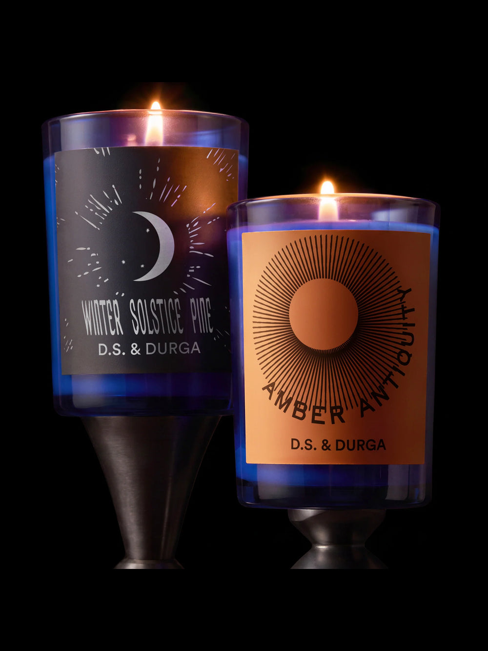 Lit D.S. & Durga Winter Solstice Pine and Amber Antiquity candles in cobalt blue glass vessels against a dark background | Twentyseven Toronto