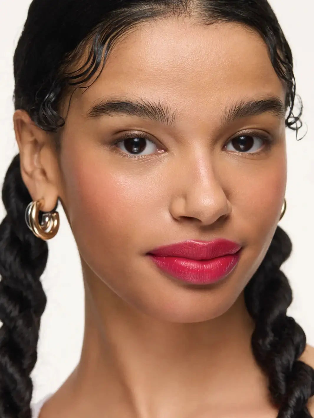 A model with dark hair styled in braids wears the glossy finish of the Wonderskin WONDER BLADING Lip Stain Masque in Neon Rose | Twentyseven Toronto
