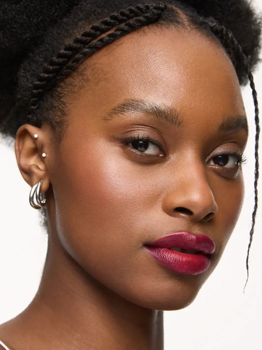 A close-up portrait of a dark-skinned model with a braided updo wearing the deep magenta of the Wonderskin WONDER BLADING Lip Stain Masque in Neon Rose | Twentyseven Toronto