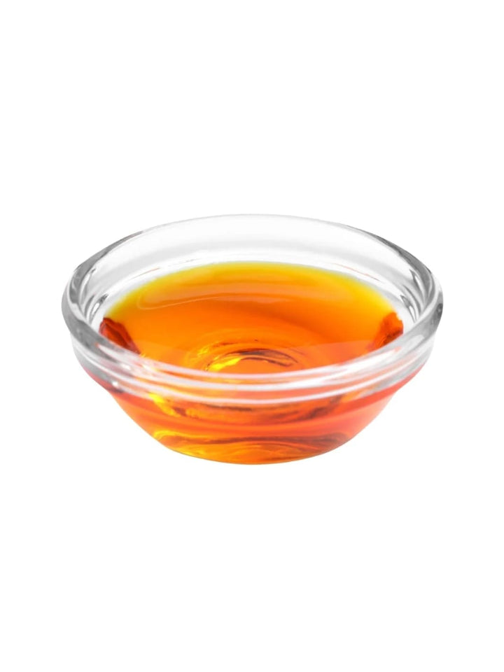 Clear glass bowl filled with amber-colored WOO World of Oils Rosehip Oil on a white background | Twentyseven Toronto