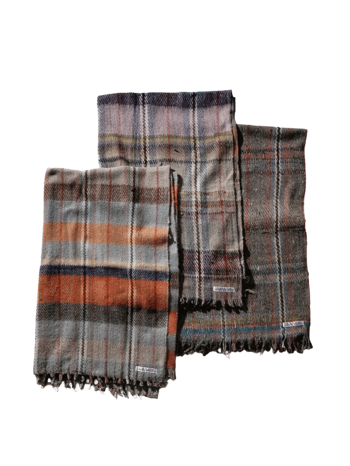 Three Puebco Recycled Wool Mix Blankets in assorted plaid patterns and muted colours, featuring grey, orange, purple and brown tones with fringed edges | Twentyseven Toronto