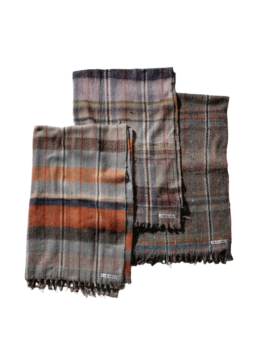 Three Puebco Recycled Wool Mix Blankets in assorted plaid patterns and muted colours, featuring grey, orange, purple and brown tones with fringed edges | Twentyseven Toronto