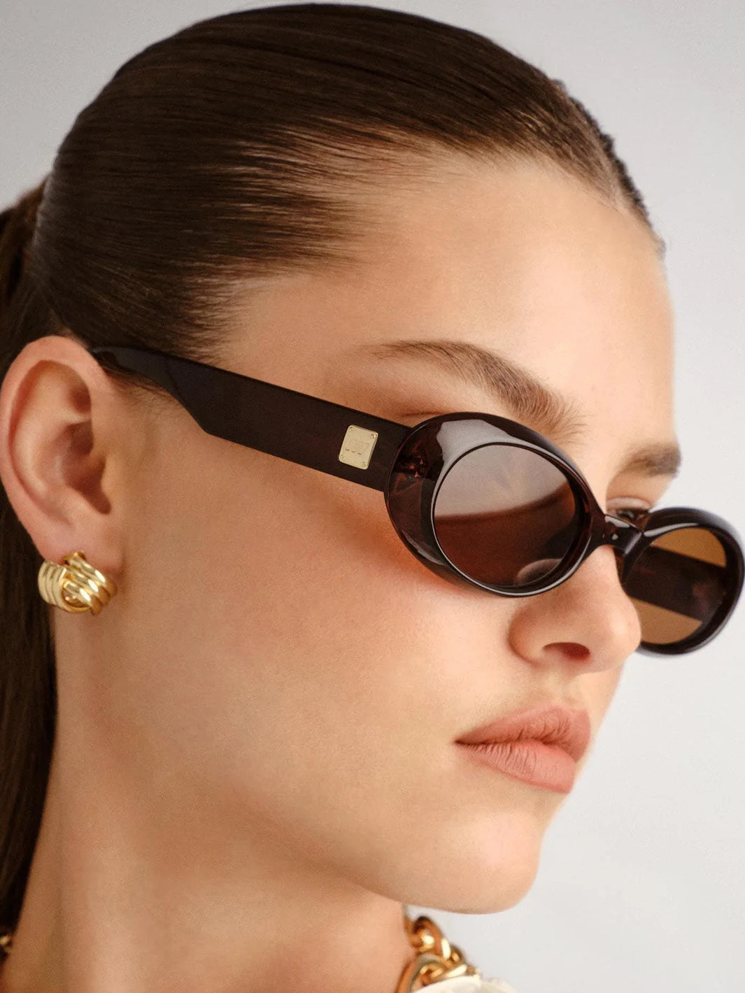 Side view of model wearing Le Specs Work It sunglasses in Cocoa with wide temples and gold logo detail | Twentyseven Toronto