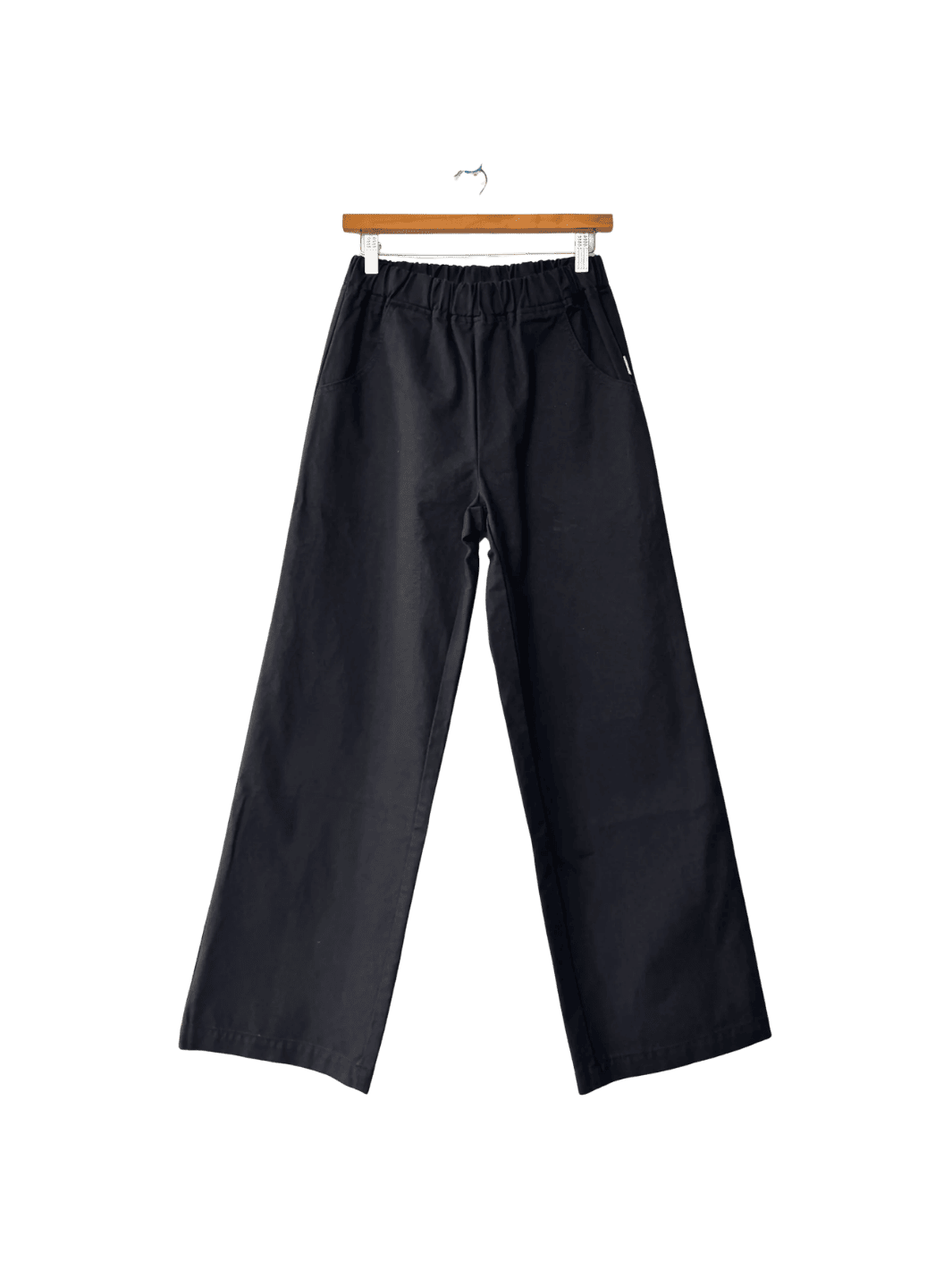 Black Le Bon Shoppe 'Work Pants' hanging on a wooden hanger against a transparent background | Twentyseven Toronto