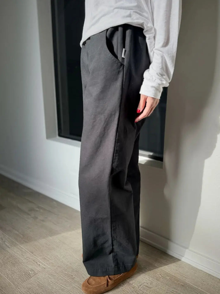 Person wearing dark gray 'Work Pants' in Black and a white shirt from Le Bon Shoppe in a minimal indoor setting | Twentyseven Toronto