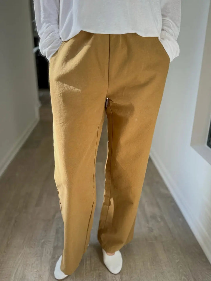 Front view of person wearing mustard yellow 'Work Pants' in 'Dijon' and a white top from Le Bon Shoppe indoors | Twentyseven Toronto