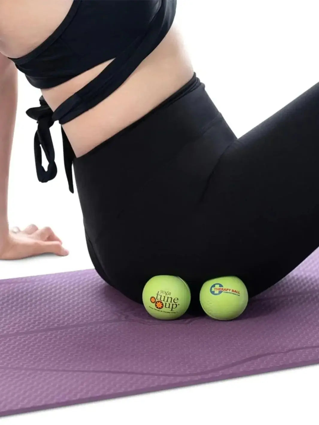 Person using two green Tune Up Fitness therapy massage balls on a purple yoga mat | Twentyseven Toronto