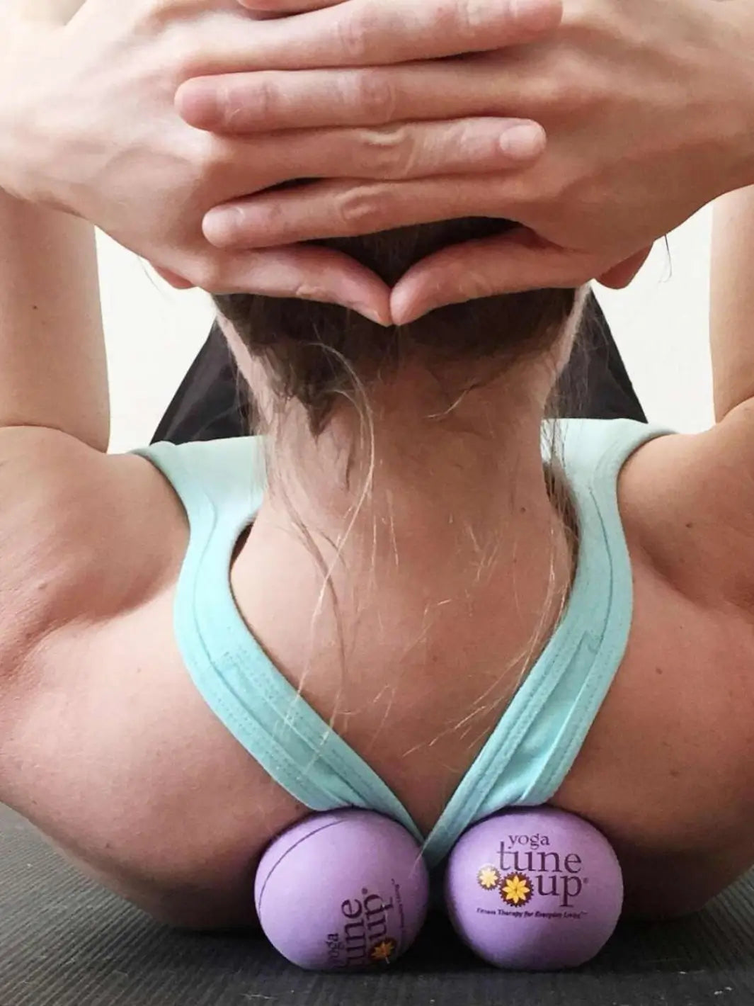 Person using Tune Up Fitness therapy massage balls on their back on a neutral background | Twentyseven Toronto