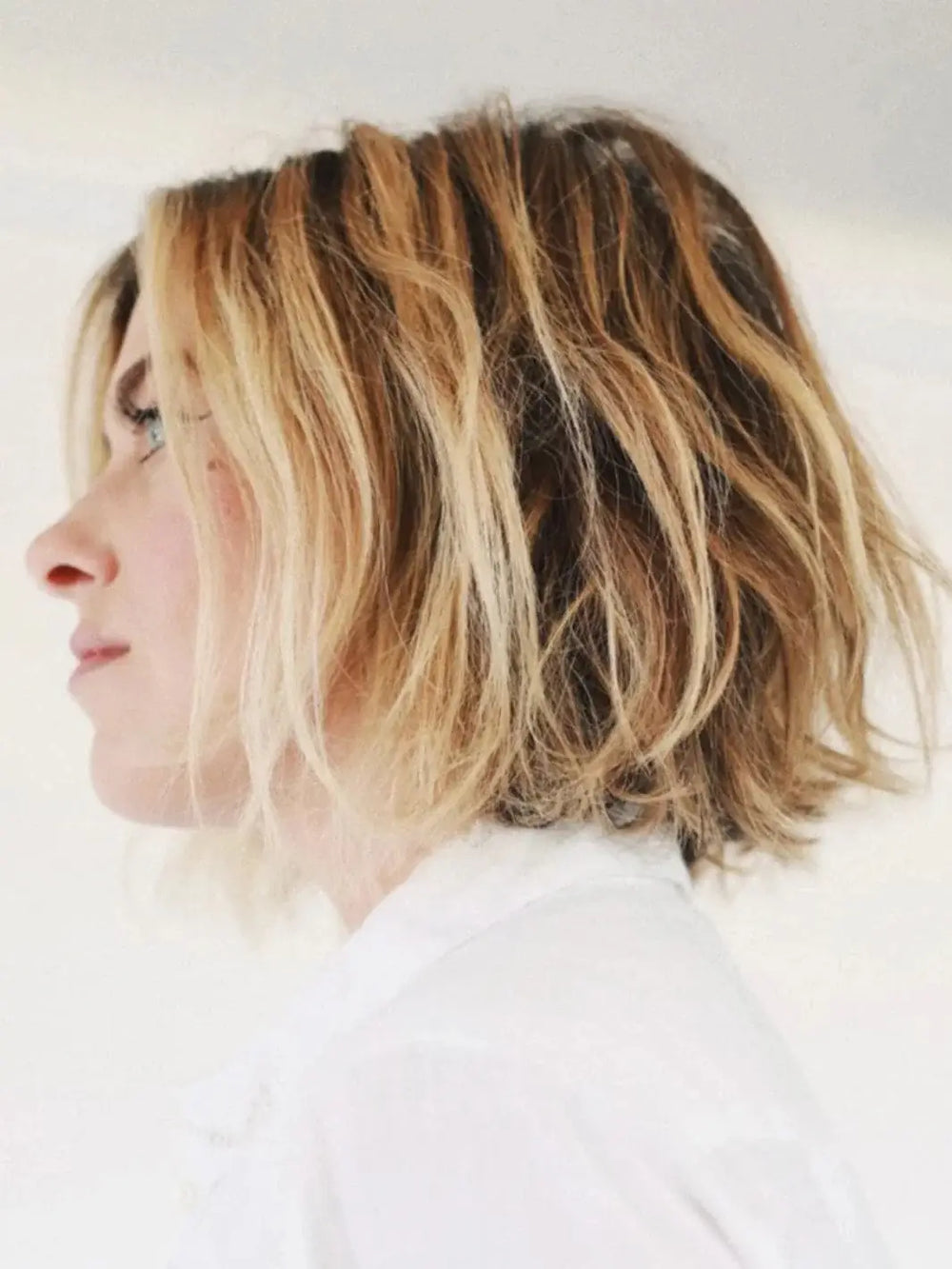 A side-profile view of a model showcasing a voluminous, textured blonde bob styled with R+Co ZIG ZAG Root Teasing and Texture Spray | Twentyseven Toronto